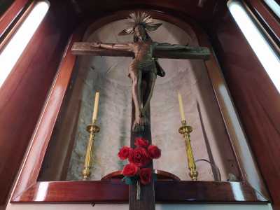 Riproduce il classico Cristo morente, con piccoli motivi dorati che decorano gli assi in corrispondenza delle mani e della testa. Affianco sono stati poi aggiunti due candelabri e al di sotto un mazzo di rose rosse